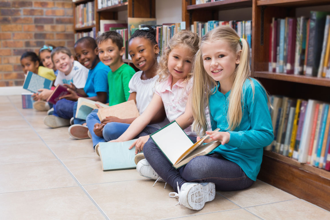 school children sitting with books in a library